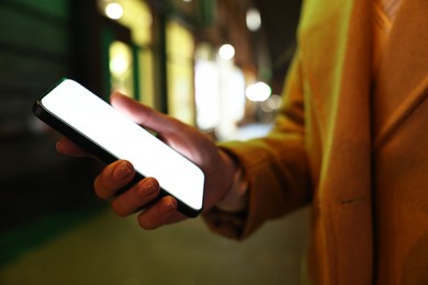 Photo of Woman with smartphone on night city street, closeup