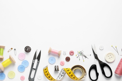 Flat lay composition with scissors and sewing supplies on white background. Space for text