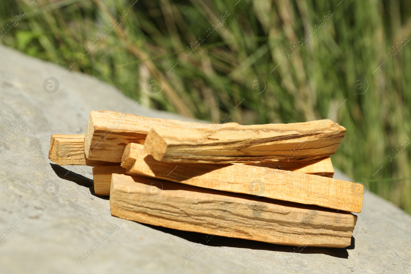 Photo of Many palo santo sticks on stone outdoors, closeup