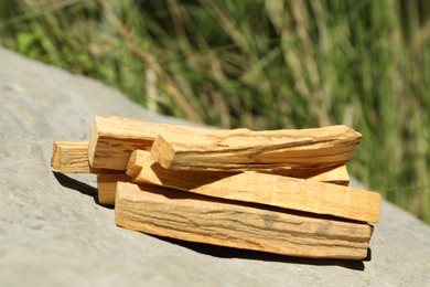 Photo of Many palo santo sticks on stone outdoors, closeup