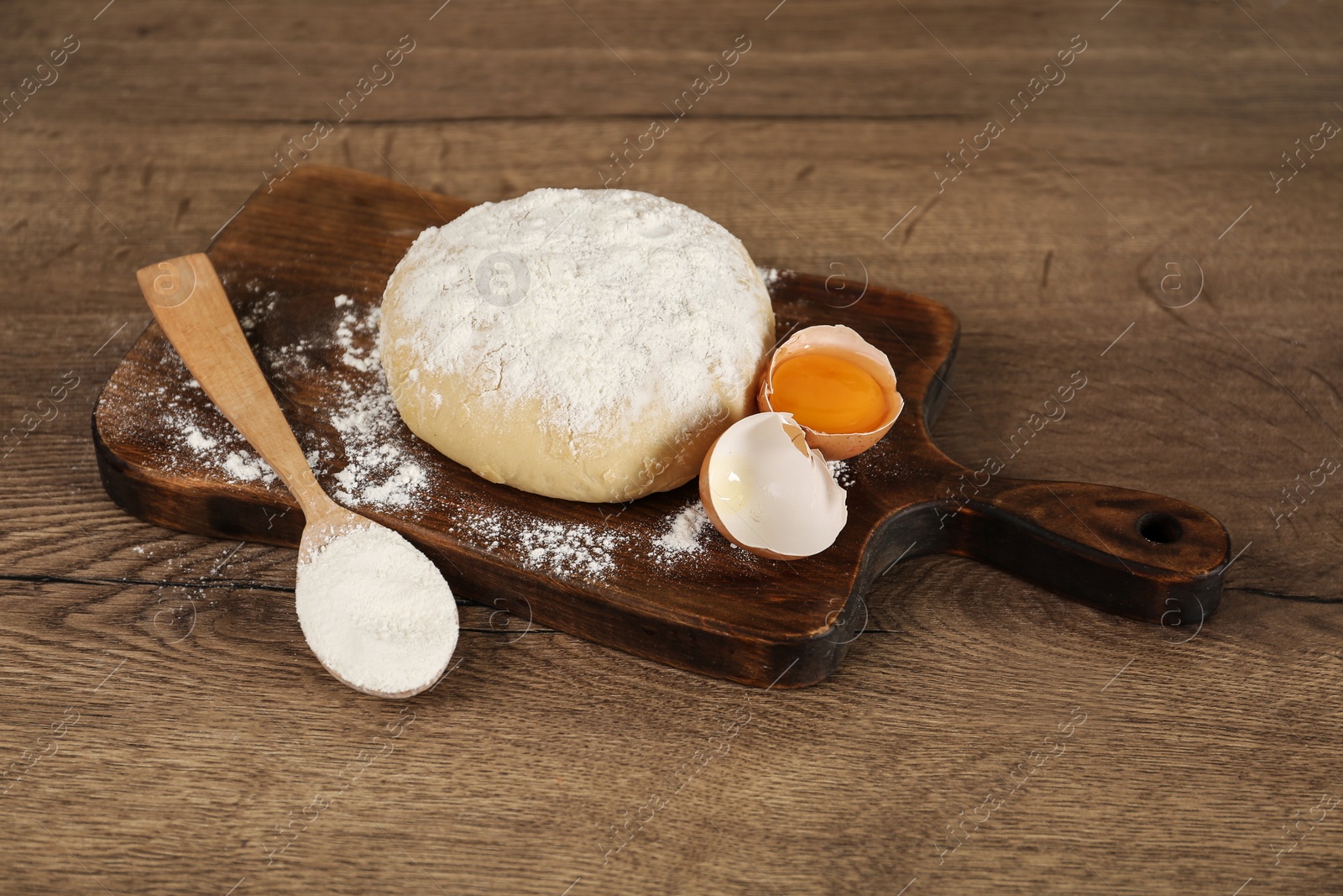 Photo of Raw egg, dough and flour on wooden table. Baking pie