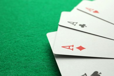 Photo of Four aces playing cards on green table. Space for text