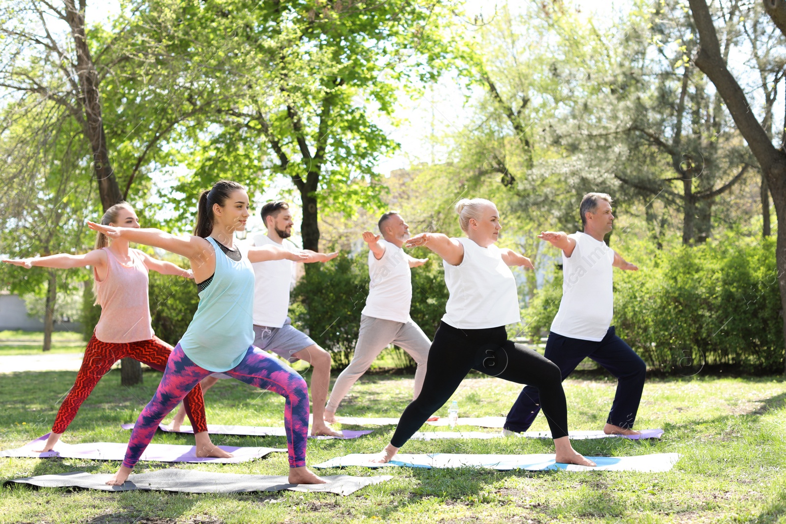 Photo of Group of people practicing yoga in park on sunny day