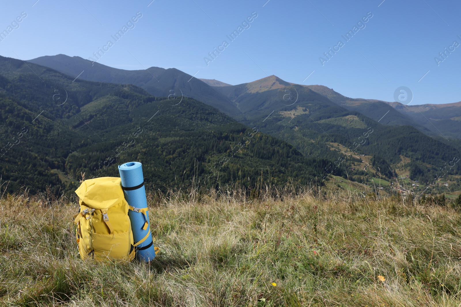 Photo of Backpack and sleeping pad in mountains on sunny day, space for text