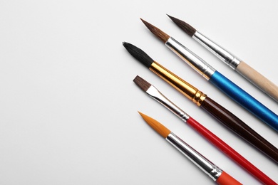 Photo of Different paint brushes on white background, top view. Space for text