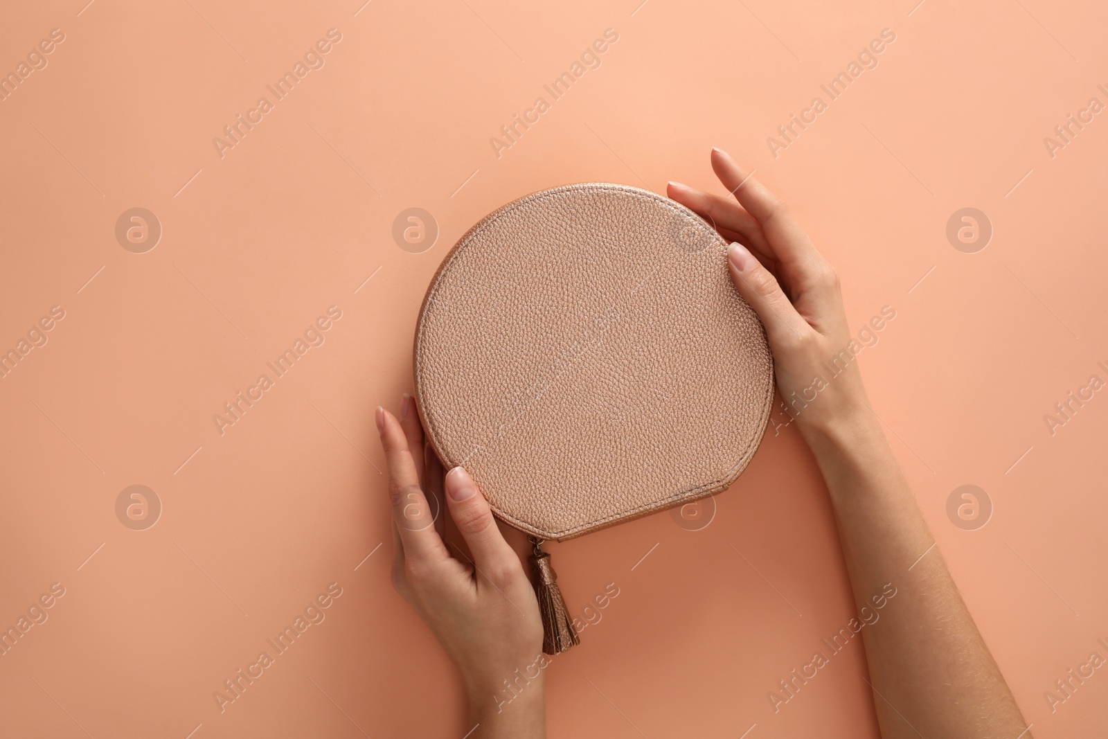 Photo of Woman holding stylish handbag on beige background, closeup