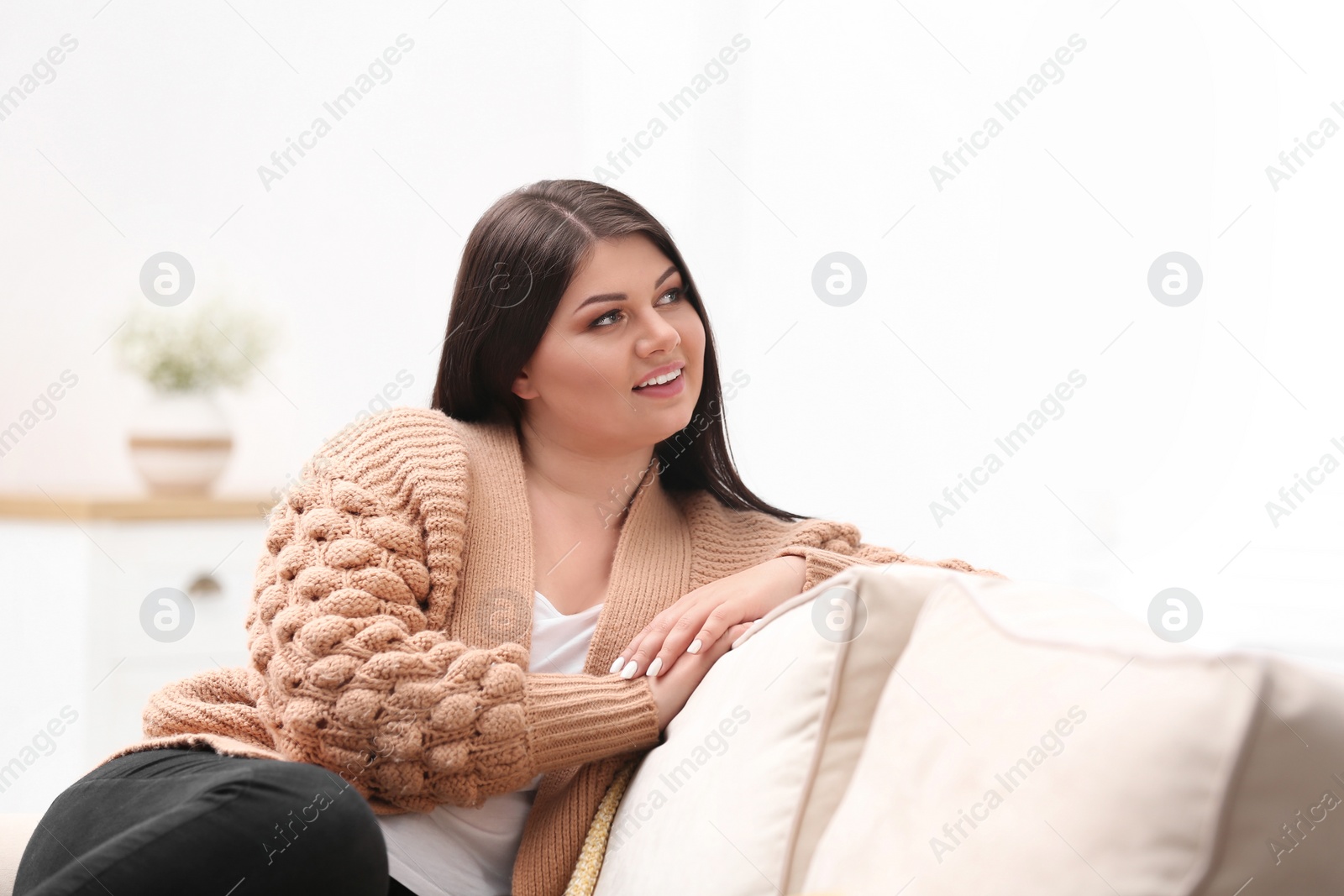 Photo of Beautiful overweight woman on sofa in living room. Plus size model