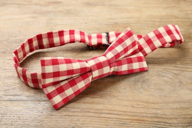 Photo of Stylish red and white gingham bow tie on wooden background, closeup