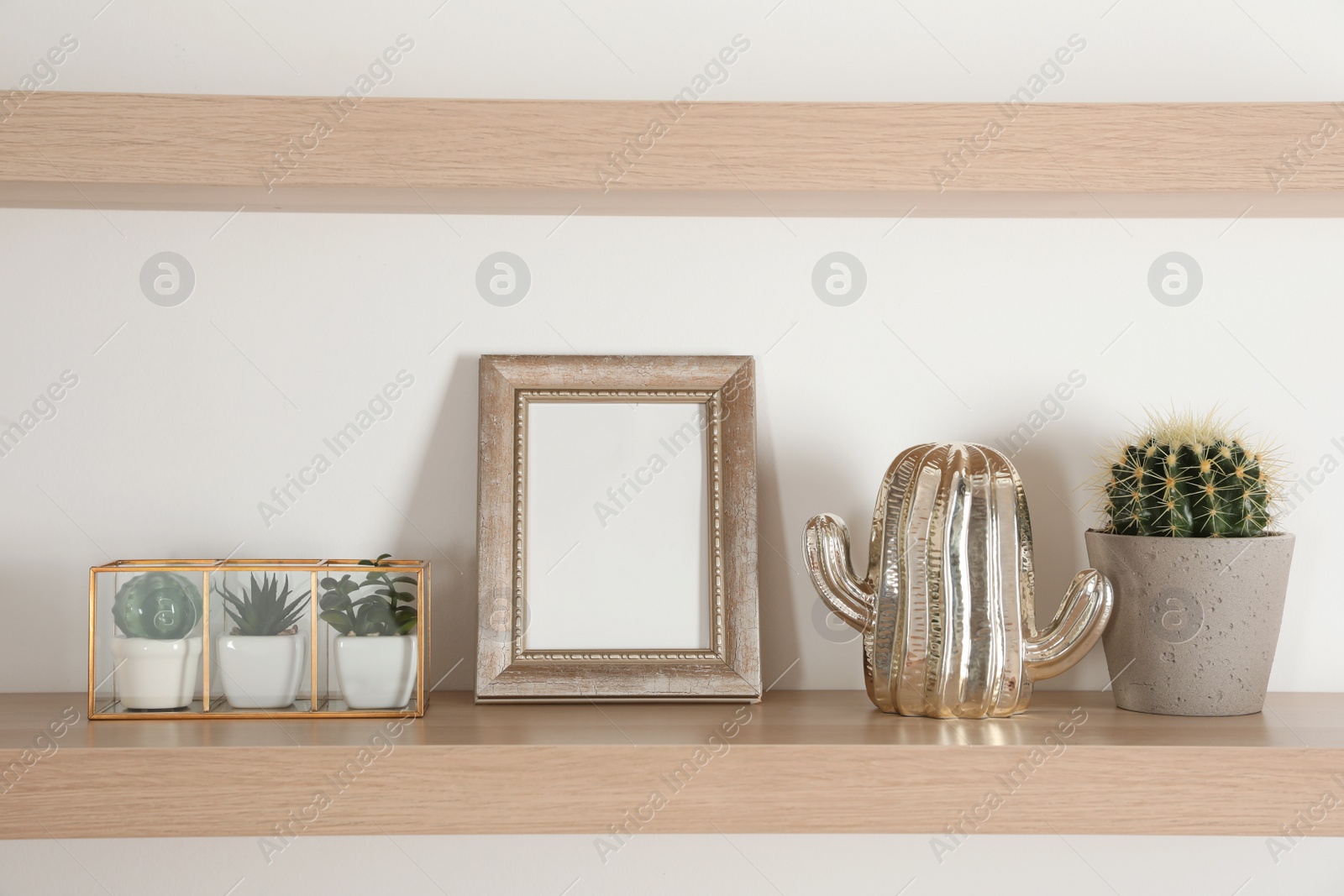 Photo of Wooden shelves with photo frame and decorative elements on light wall