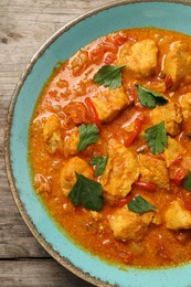 Photo of Delicious chicken curry on wooden table, top view