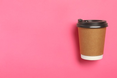 Takeaway paper coffee cup on pink background, top view. Space for text