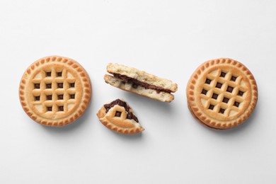 Tasty sandwich cookies with cream on white background, flat lay