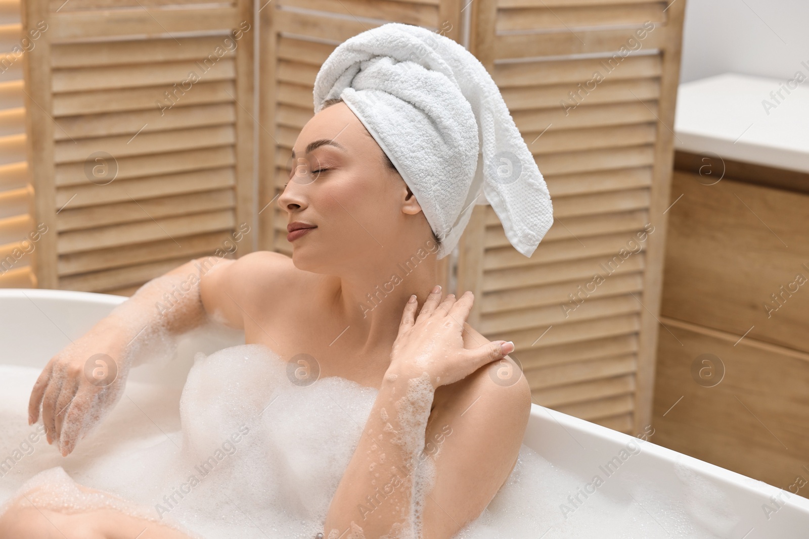 Photo of Beautiful woman taking bath with foam in tub indoors, space for text