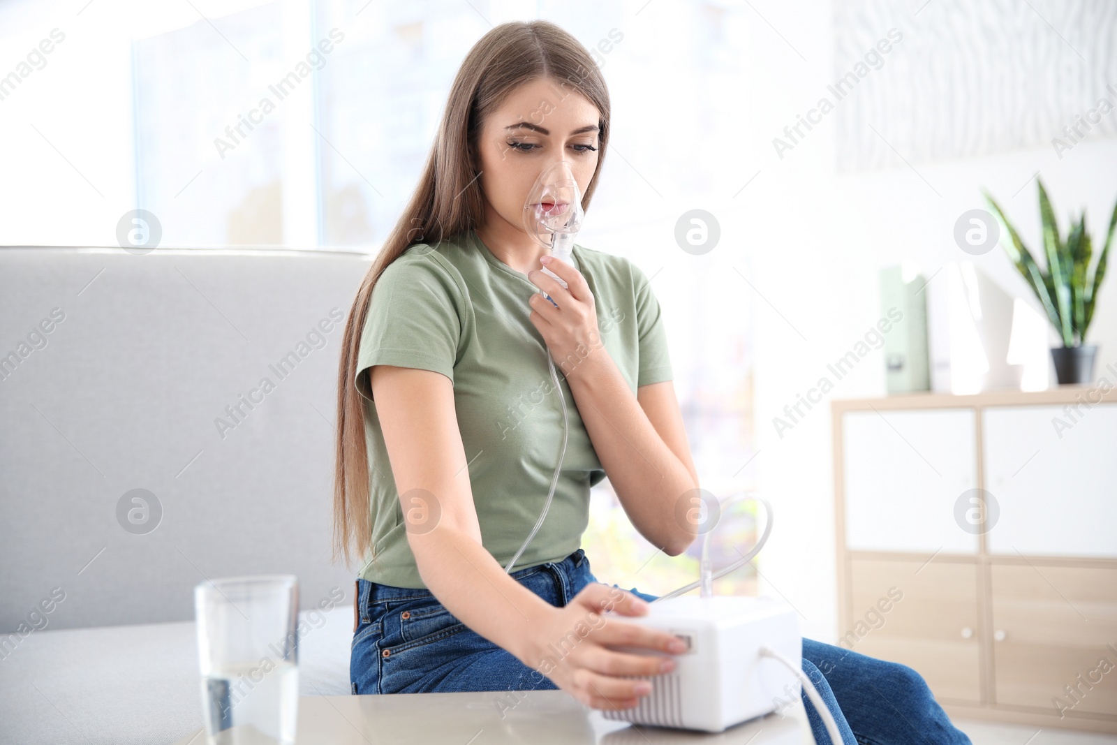 Photo of Young woman with asthma machine in light room