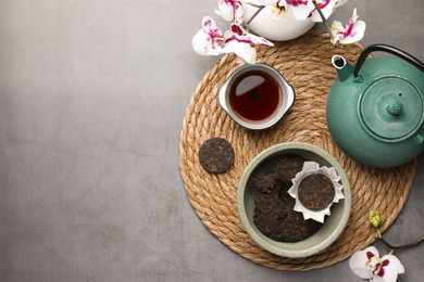 Photo of Flat lay composition with aromatic pu-erh tea on grey table. Space for text
