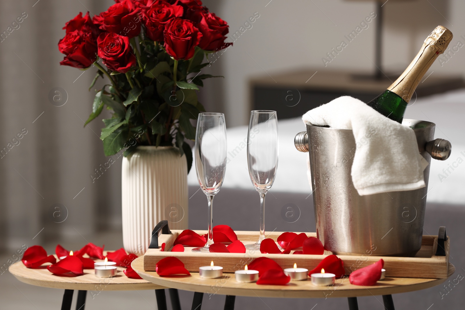 Photo of Honeymoon. Sparkling wine, glasses and bouquet of roses on wooden table in room