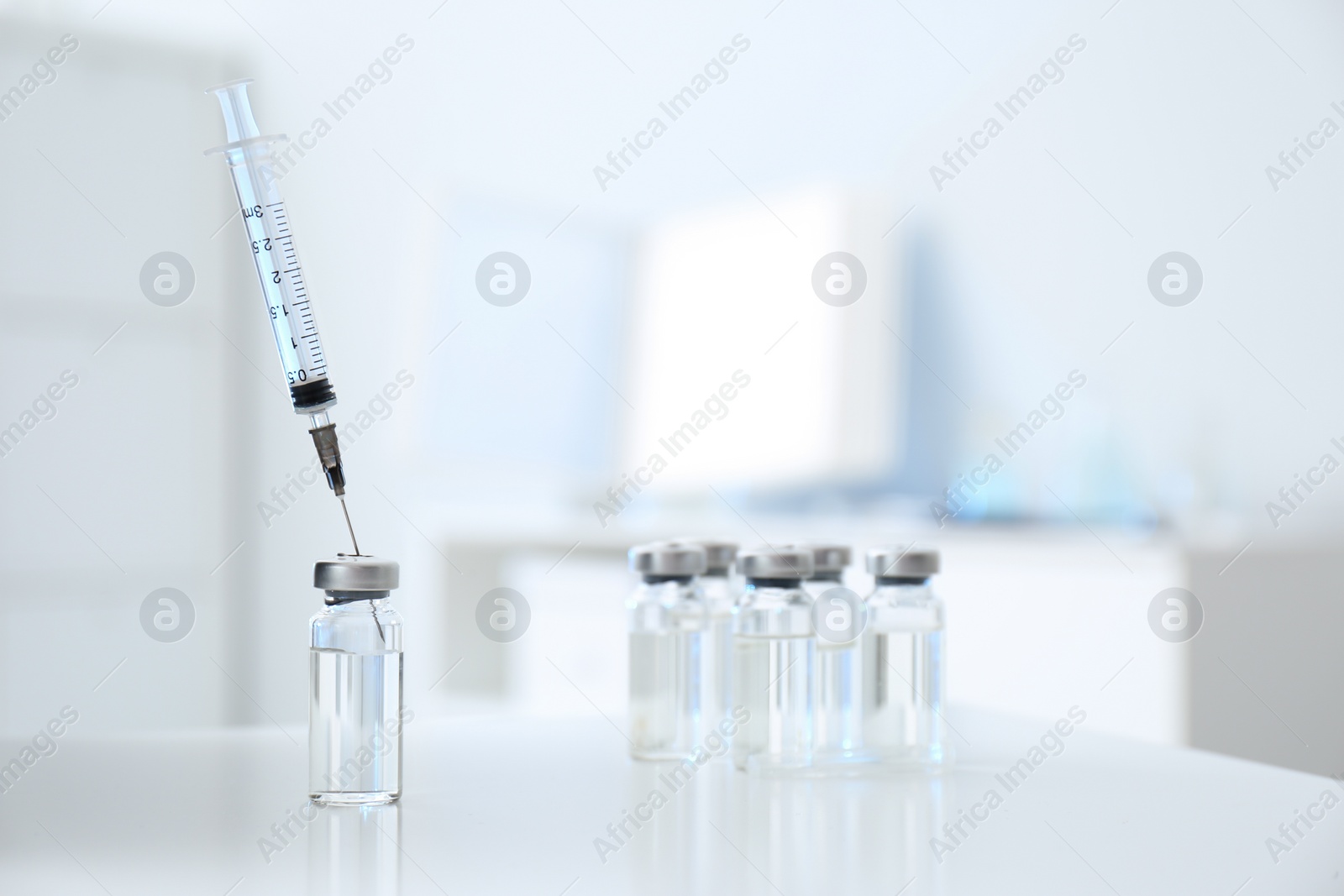 Photo of Syringe with vial of medicine on white table