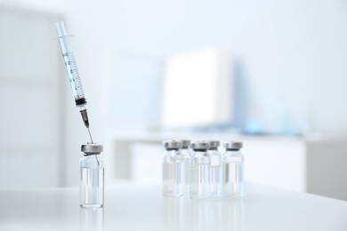 Syringe with vial of medicine on white table