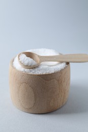 Photo of Organic white salt in bowl and spoon on light grey background, closeup. Space for text