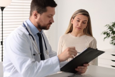 Photo of Professional doctor working with patient at white table in hospital