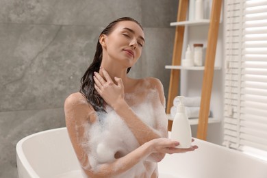 Photo of Woman taking bath with shower gel in bathroom