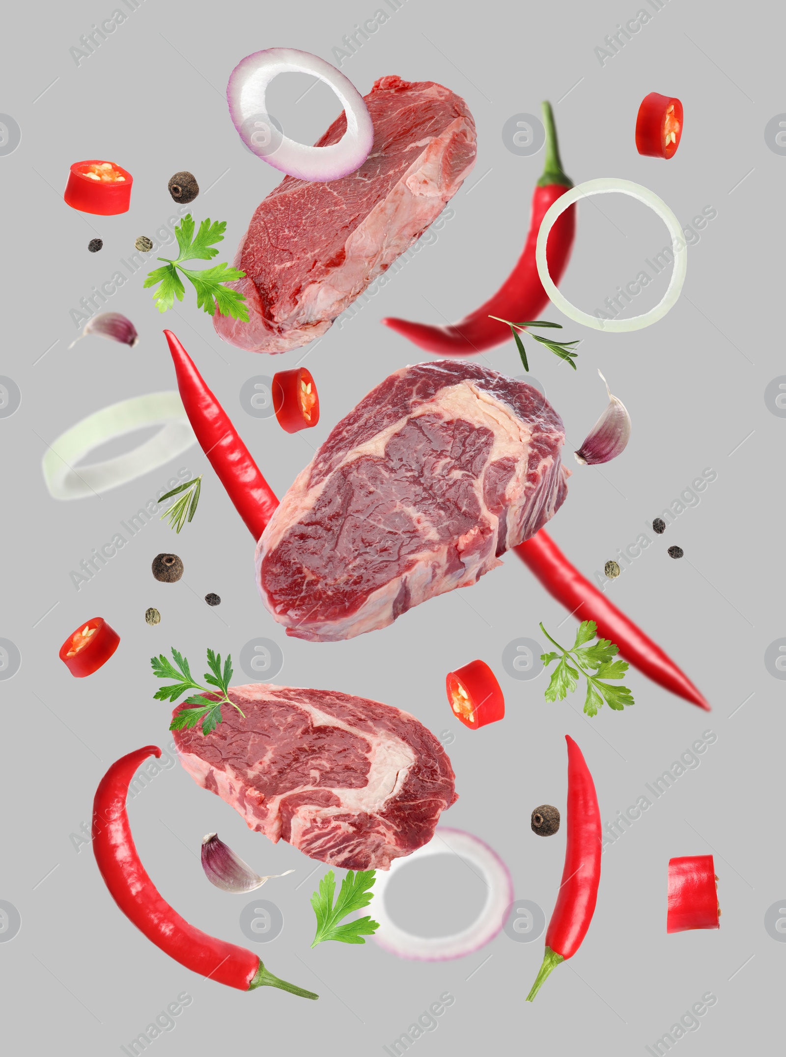 Image of Beef meat and different spices falling on grey background