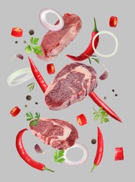 Beef meat and different spices falling on grey background