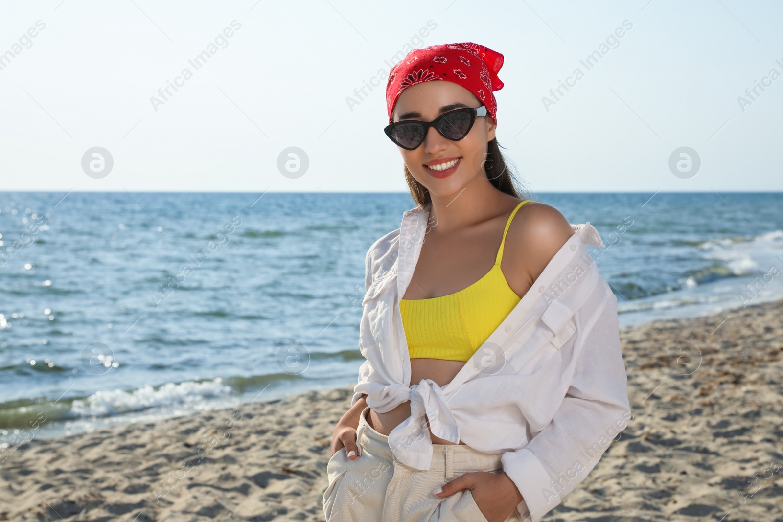 Photo of Young woman with sunglasses and bandana at beach. Sun protection care