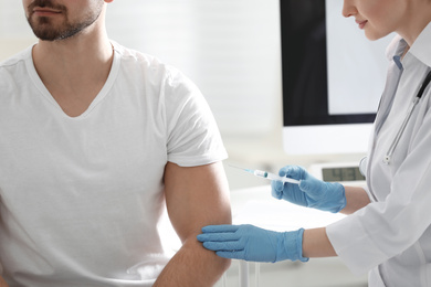 Doctor giving injection to patient in hospital, closeup. Vaccination concept