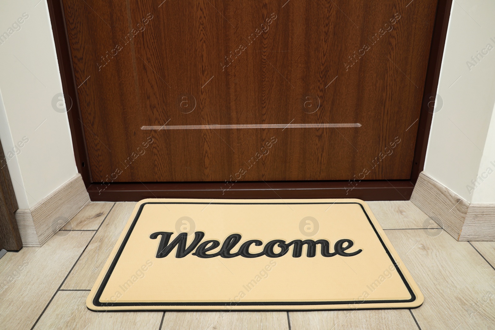 Photo of Beautiful beige doormat with word Welcome on floor near entrance