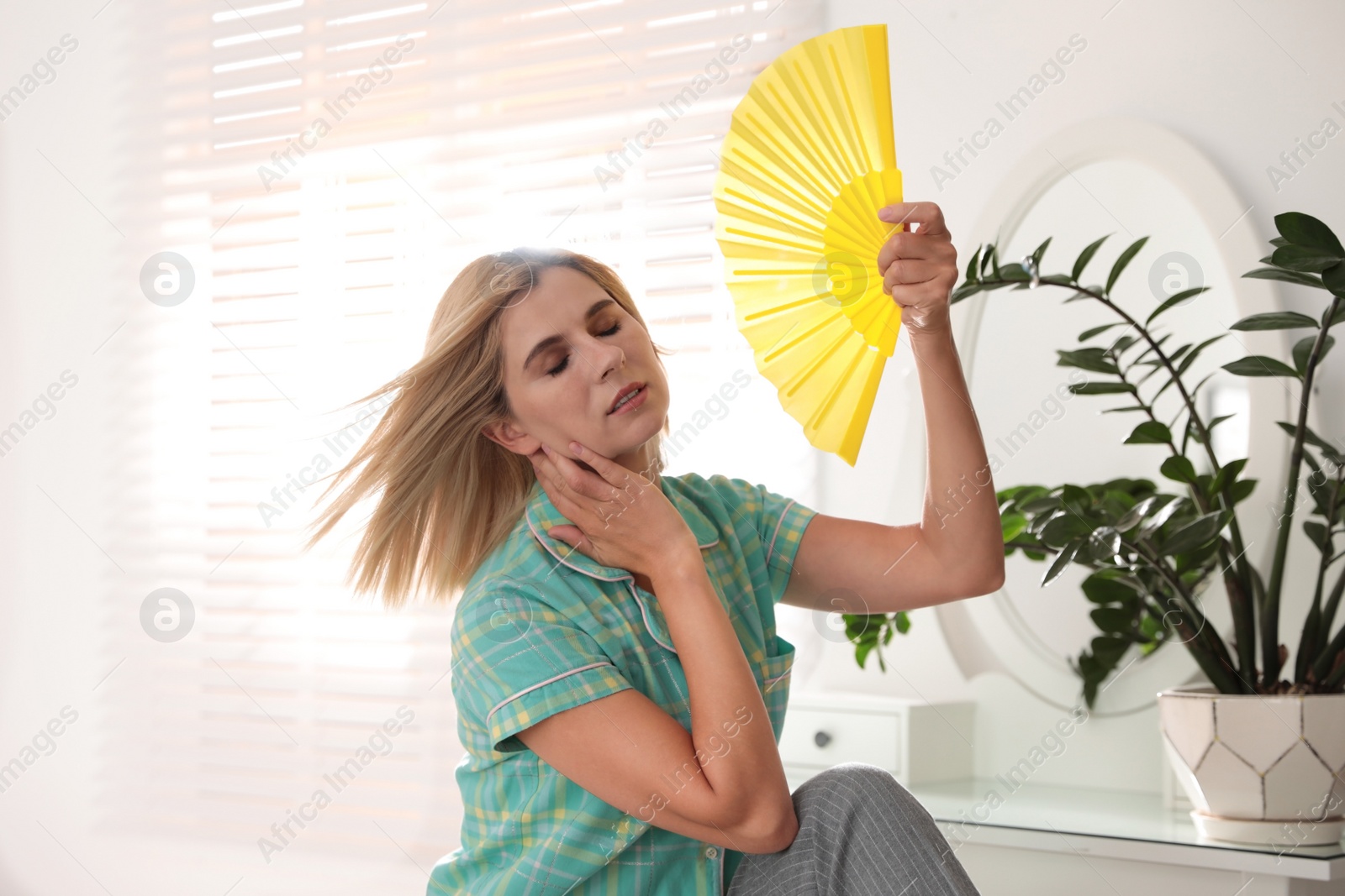 Photo of Woman with hand fan suffering from heat at home. Summer season