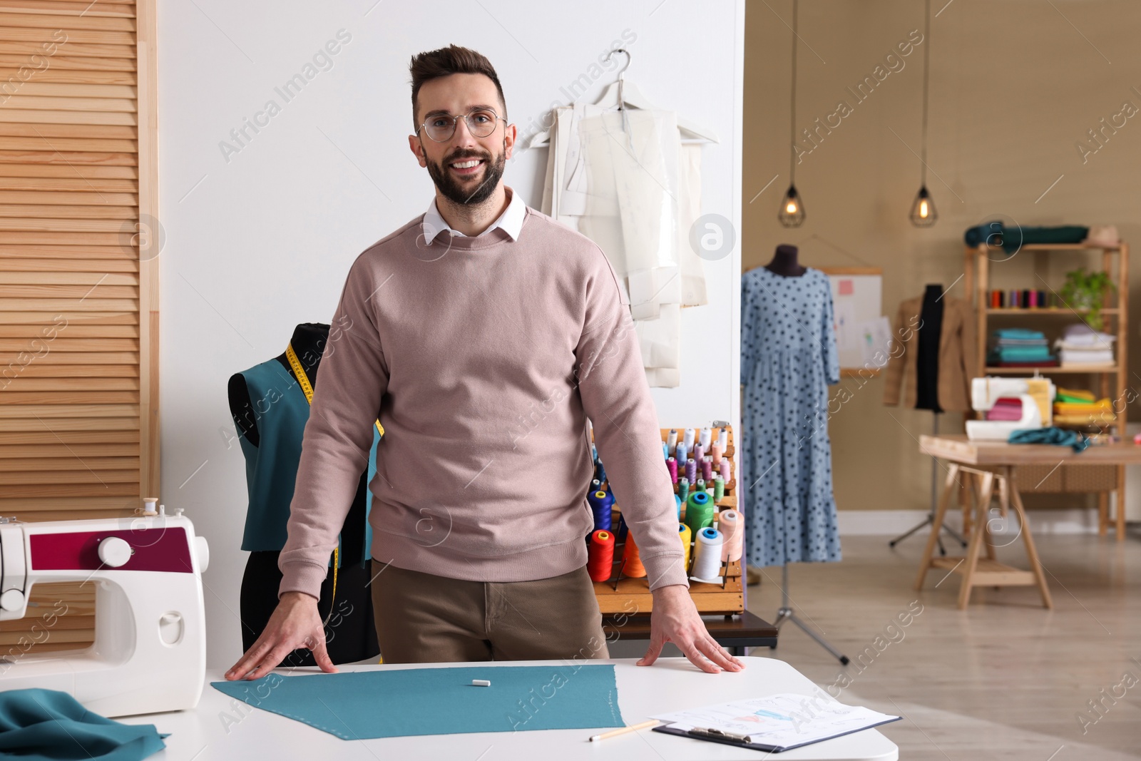 Photo of Portrait of professional dressmaker near table in workshop