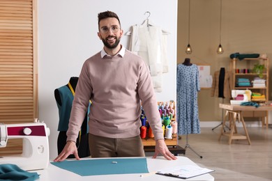 Portrait of professional dressmaker near table in workshop