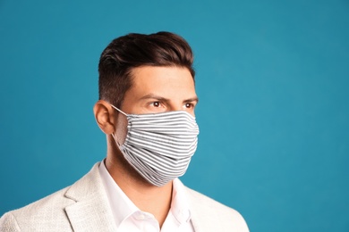 Photo of Man in protective face mask on blue background. Space for text