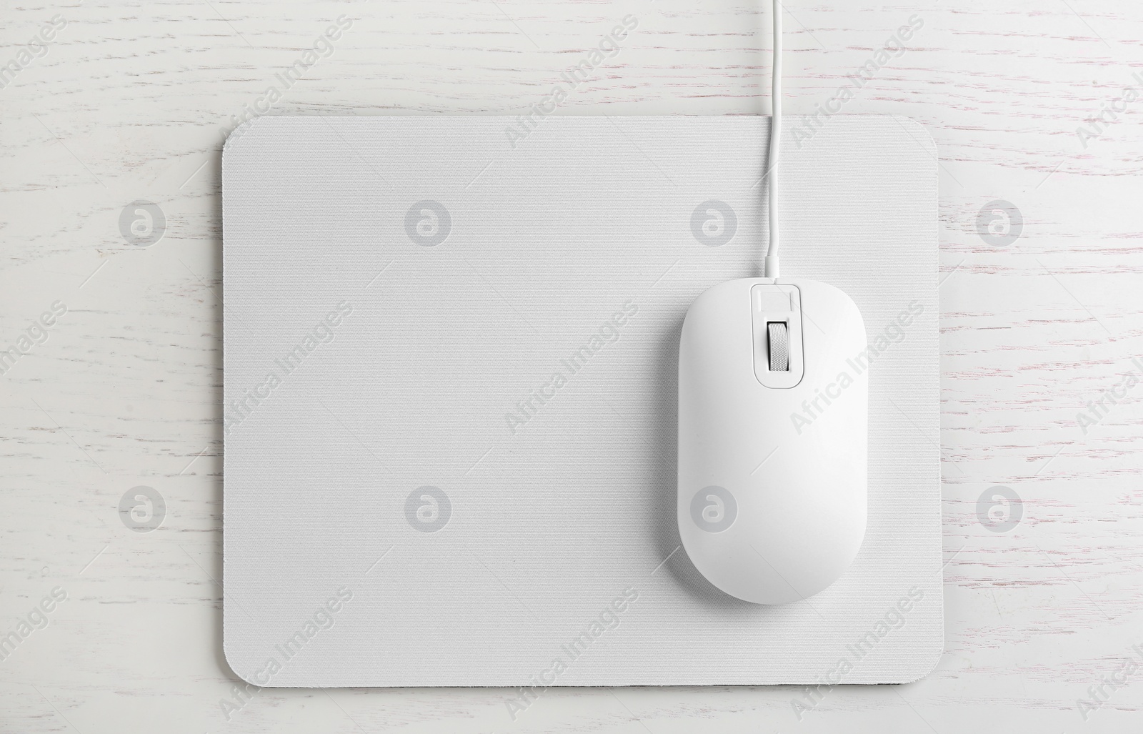 Photo of Modern wired optical mouse and pad on white wooden table, top view