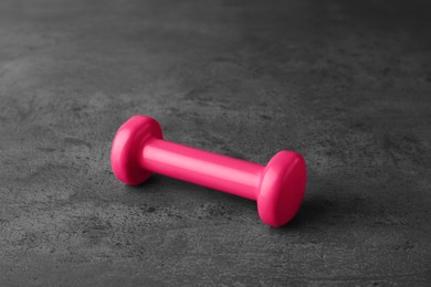 One pink vinyl dumbbell on grey table