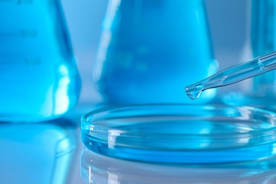 Photo of Dripping liquid from pipette into petri dish in laboratory, closeup