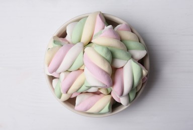 Bowl with colorful marshmallows on white wooden table, top view