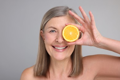 Photo of Beautiful woman with half of orange rich in vitamin C on grey background