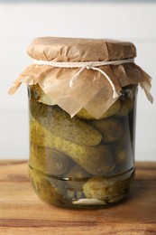 Photo of Tasty pickled cucumbers in jar on wooden table