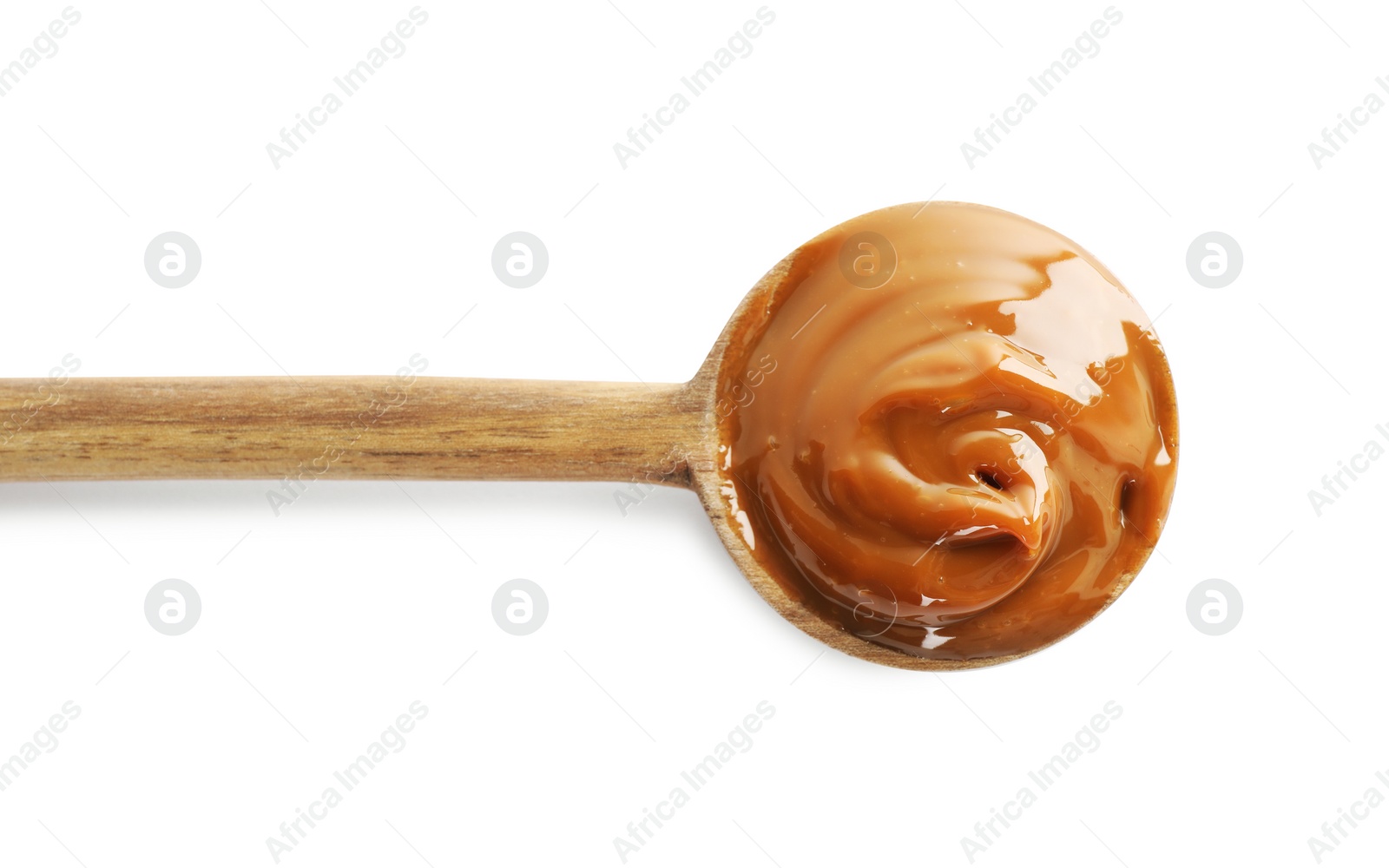 Photo of Wooden spoon with tasty boiled condensed milk isolated on white, top view