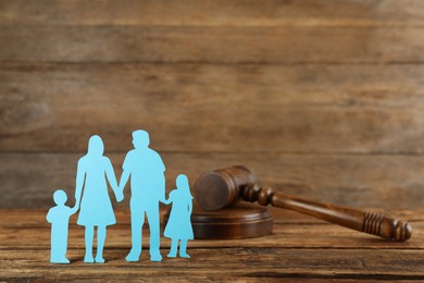 Photo of Paper family figure and gavel on wooden table. Child adoption concept