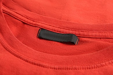 Photo of Blank clothing label on red T-shirt, closeup