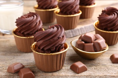 Photo of Delicious cupcakes and chocolate pieces on wooden table, closeup