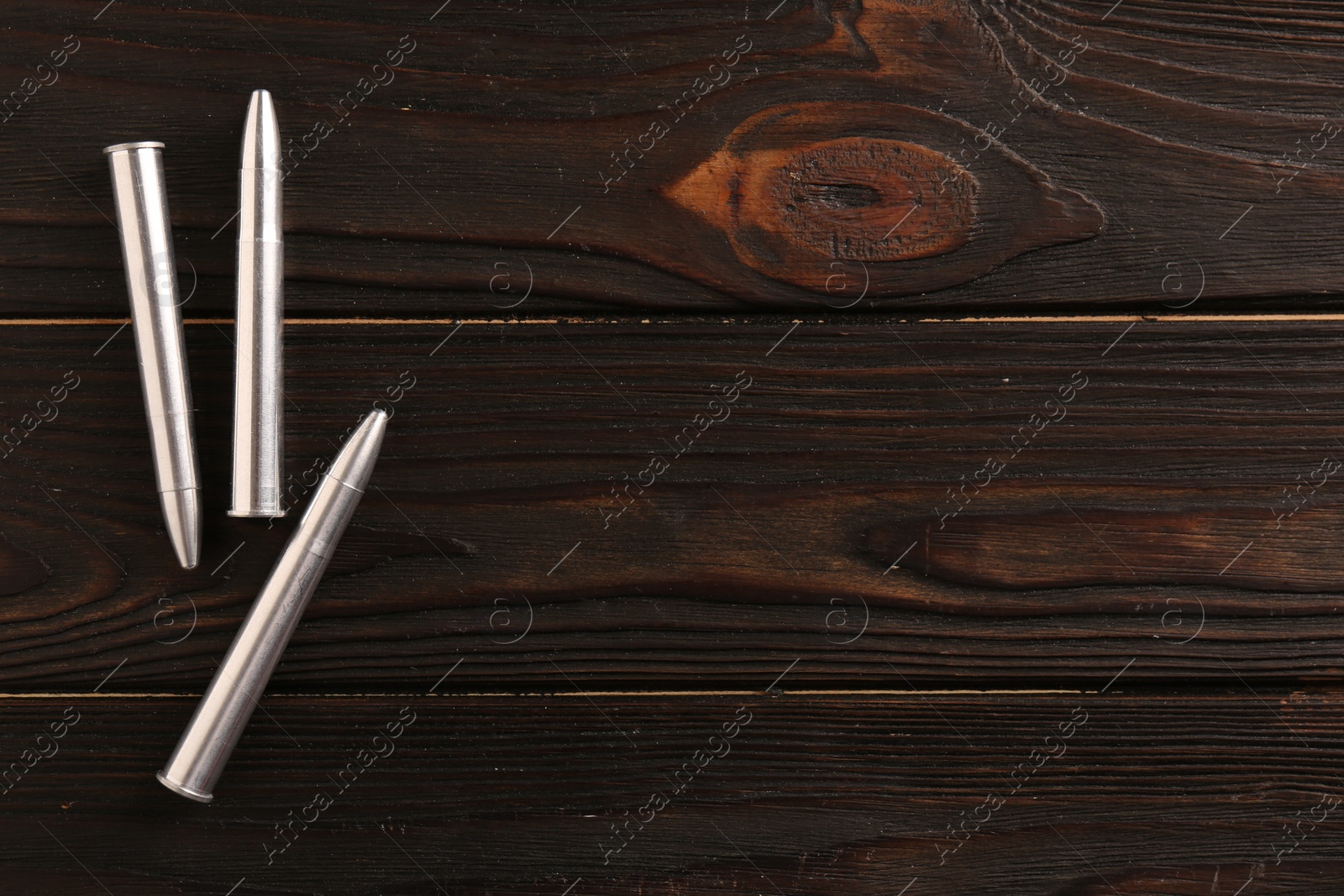 Photo of Metal bullets on dark wooden table, flat lay. Space for text