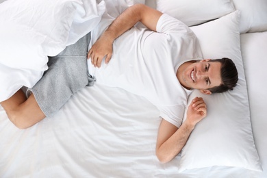 Photo of Portrait of handsome man lying on large bed, above view