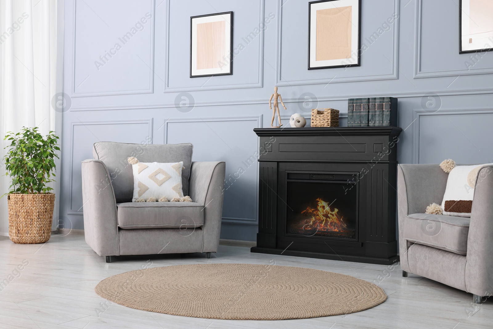 Photo of Black stylish fireplace near armchairs in cosy living room