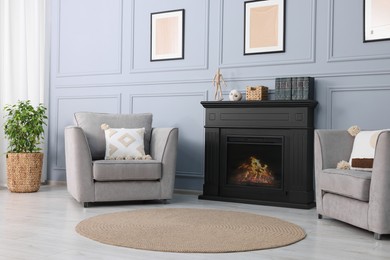 Black stylish fireplace near armchairs in cosy living room