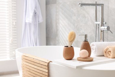 Photo of Different personal care products and accessories on bath tub in bathroom, space for text