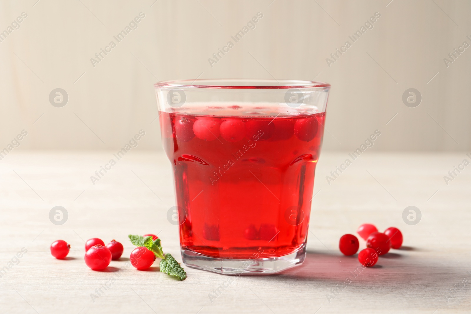 Photo of Tasty refreshing cranberry juice, mint and fresh berries on light wooden table